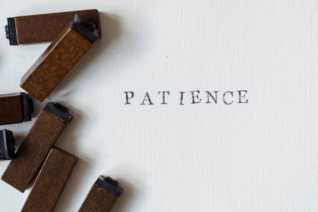 Letterpress Patience on white surface with wooden blocks for a vintage feel.